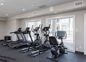 Thumbnail 4 of 21 - A spacious gym with treadmills, elliptical machines, and other exercise equipment.
